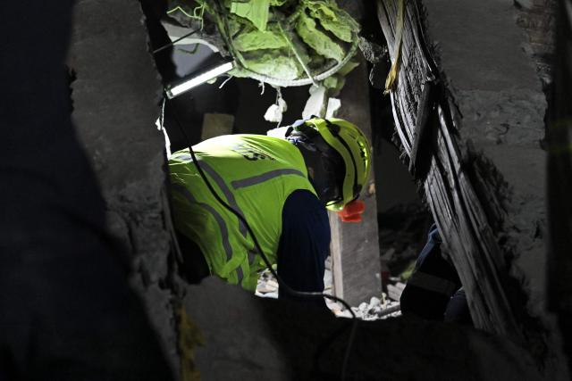 A rescue worker searches for survivors at the site of collapsed buildings after an earthquake in Cali, Colombia on August 12, 2026. Rescuers, soldiers and volunteers searched through collapsed apartment blocks and office buildings across western Colombia, racing to find survivors after the country's strongest earthquake in a century killed at least 239 people and left many more homeless on August 10, 2026. The 7.4-magnitude quake injured more than 1,670 people, according to a tally by municipal authorities. (Photo by Raul ARBOLEDA / AFP)