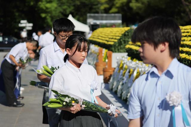 Representatives of Hiroshima's children offer flowers at the Peace Memorial Ceremony, on the 81st anniversary of the dropping of the atomic bomb, at the Peace Memorial Park in Hiroshima on August 6, 2026. (Photo by Jiji / AFP) / Japan OUT