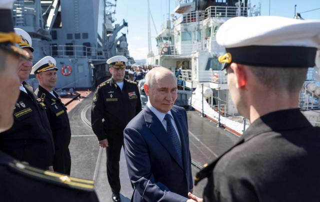 In this pool photograph distributed by the Russian state agency Sputnik, Russia's President Vladimir Putin shakes hands with officers onboard the Russian Navy's guided missile cruiser Varyag during the final stage of a Pacific Fleet's naval drills on far eastern Sakhalin Island on August 13, 2026. (Photo by Gavriil Grigorov / POOL / AFP)
