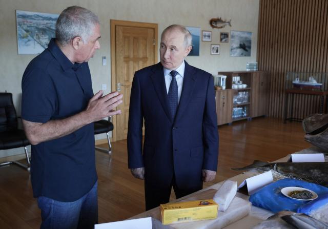 In this pool photograph distributed by the Russian state agency Sputnik, Russia's President Vladimir Putin visits the Yasny fish processing factory on Iturup island, one of four islands in the contested chain known as the Kuril Islands in Russia and the Northern Territories in Japan, on August 13, 2026. (Photo by Gavriil Grigorov / POOL / AFP)