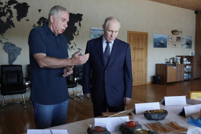 In this pool photograph distributed by the Russian state agency Sputnik, Russia's President Vladimir Putin visits the Yasny fish processing factory on Iturup island, one of four islands in the contested chain known as the Kuril Islands in Russia and the Northern Territories in Japan, on August 13, 2026. (Photo by Gavriil Grigorov / POOL / AFP)