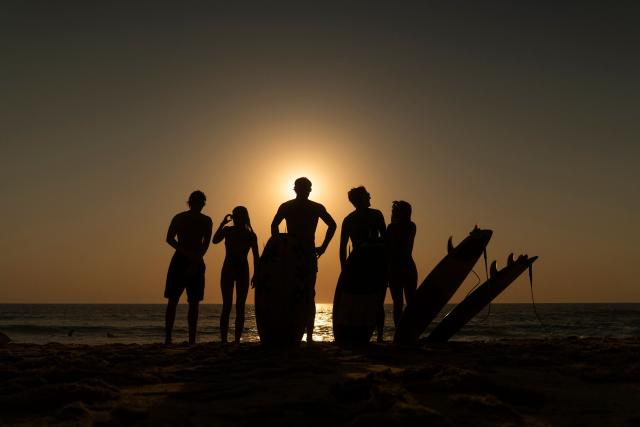 surfers watch a partial solar eclipse from the beach in Lege-Cap-Ferret on August 12, 2026. Millions of people turn their gaze towards the heavens on August 12, 2026 to witness one of nature's greatest spectacles -- a rare total solar eclipse -- as it sweeps over mainland Europe to briefly turn day into night. (Photo by Tania Buijten / AFP)