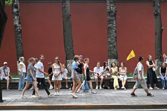 Foreign tourists walk past Jingshan park in Beijing on August 13, 2026. (Photo by Adek BERRY / AFP)
