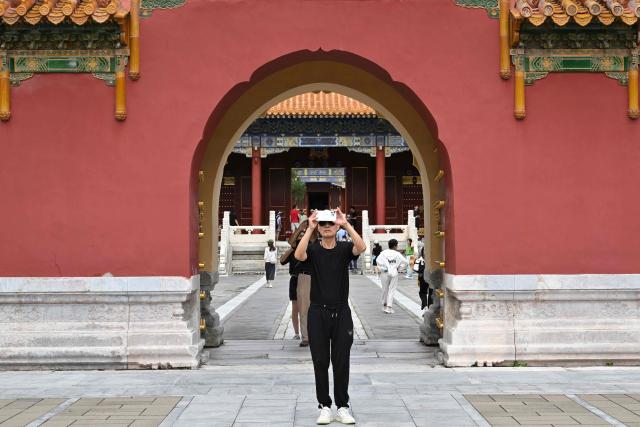 People take pictures as they visit the Jingshan park in Beijing on August 13, 2026. (Photo by Adek BERRY / AFP)