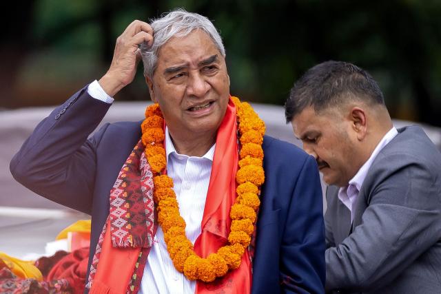 Former Nepal's prime minister Sher Bahadur Deuba (L) gestures upon his arrival outside the airport in Kathmandu on August 13, 2026. Deuba, facing arrest for alleged corruption, returned home on August 13, six months after leaving for medical treatment abroad. (Photo by Prabin Ranabhat / AFP)