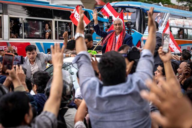Former Nepal's prime minister Sher Bahadur Deuba (C) waves to supporters outside the airport upon his arrival in Kathmandu on August 13, 2026. Deuba, facing arrest for alleged corruption, returned home on August 13, six months after leaving for medical treatment abroad. (Photo by Prabin RANABHAT / AFP)