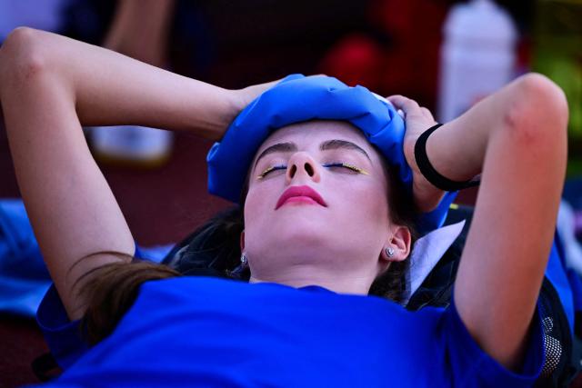 Ukraine's Yaroslava Mahuchikh holds an ice pack on her head to cool down as she waits for her turn to compete in the women's high jump qualifier during the European Athletics Championships at Alexander Stadium in Birmingham on August 13, 2026. (Photo by Ben STANSALL / AFP)