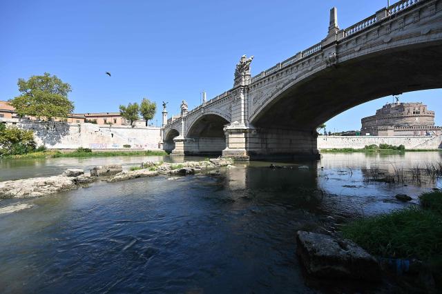 This photograph shows an Ancient Roman bridge emerging from the Tiber River, near the Castel Sant'Angelo (R), in central Rome on 13 August, 2026. The unusually low waters of the Tiber River have revealed the remains of an ancient Roman bridge believed to date back to the reign of Emperor Nero (54-68 AD). Located near Castel Sant'Angelo, the structure once carried the ancient Via Triumphalis across the river, linking Rome with the Vatican area nearly 2000 years ago. (Photo by Andreas SOLARO / AFP)