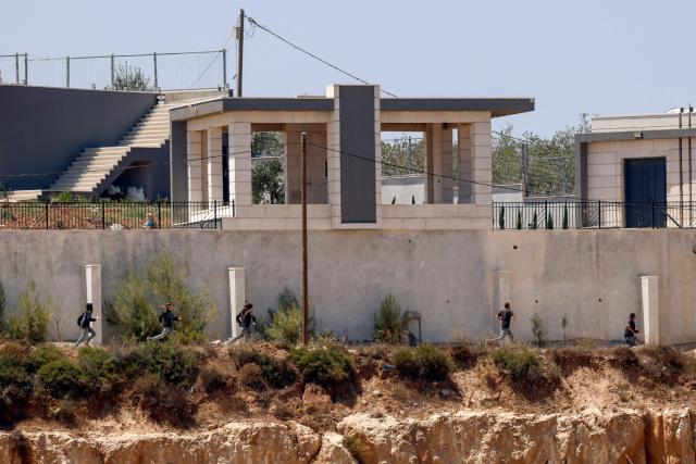 Israeli settlers run as being chased by an Israeli military vehicle around Palestinian houses in the village of Qusra, south of Nablus, in the occupied West Bank, on August 13, 2026. Israel has occupied the West Bank since 1967. More than 500,000 Israelis live in settlements in the territory, which are illegal under international law, among some three million Palestinians. Violence against Palestinians by Israeli settlers has increased dramatically since the October 7, 2023 attack on Israel by Hamas from the Gaza Strip. (Photo by Zain JAAFAR / AFP)