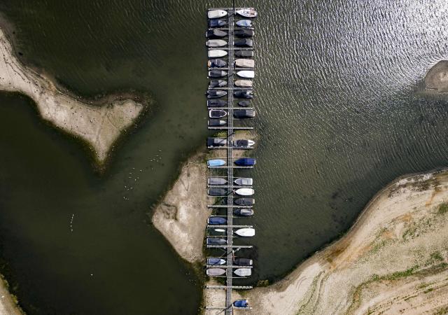 This aerial photograph shows the low water level at the recreational lake De Bijland in Tolkamer on August 4, 2026. The Netherlands, renowned for its resilience in the face of the constant threat of flooding, has been grappling for several months with a historic drought caused by very low rainfall and exceptional heat, which has completely dried out the soil since spring. (Photo by Emiel Muijderman / ANP / AFP) / Netherlands OUT