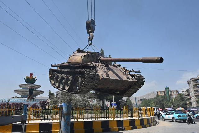 Afghans use a crane to place a Soviet-era military tank at a square in Kabul on August 13, 2026 ahead of the fifth anniversary marking the Taliban's return to power. (Photo by Wakil KOHSAR / AFP)