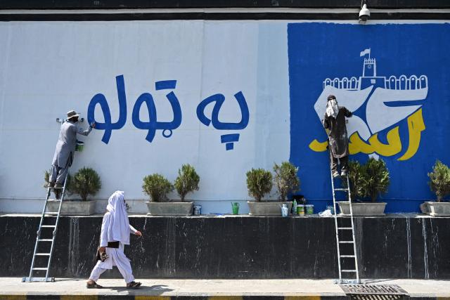 Afghan men paint wall murals along a road in Kabul on August 13, 2026 ahead of the fifth anniversary marking the Taliban's return to power. (Photo by Wakil KOHSAR / AFP)