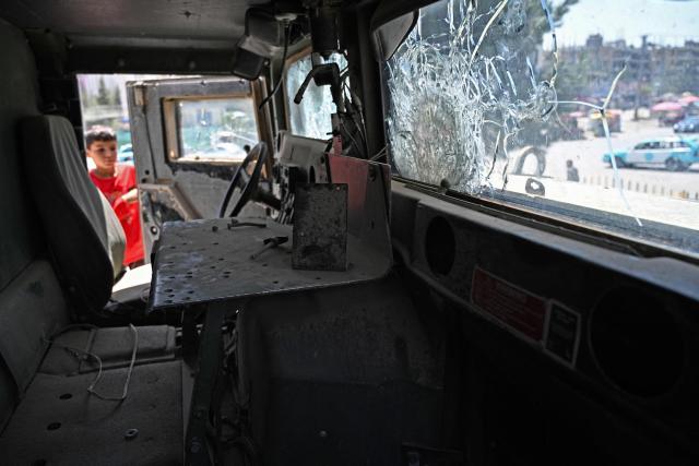 An Afghan boy looks at a damaged armored Humvee displayed at a square in Kabul on August 13, 2026 ahead of the fifth anniversary marking the Taliban's return to power. (Photo by Wakil KOHSAR / AFP)