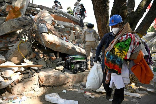 A rescuer collects personal belongings from the rubble from a damaged building in Cali, Colombia, on August 13, 2026, three days after a 7.4 earthquake. Rescuers in Colombia were making last-ditch efforts to locate earthquake survivors early on August 13, 2026, as the critical 72-hour window for rescue operations neared its end. (Photo by Raul ARBOLEDA / AFP)