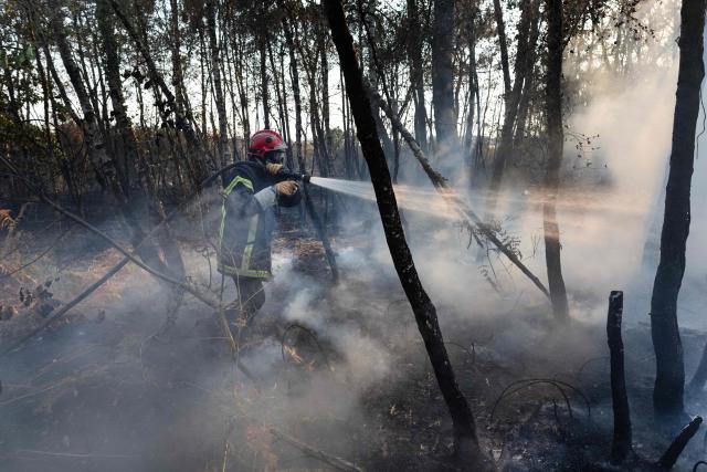 A firefighter sprays water on a burnt forested area following a wildfire in Saint-Just, western France, August 13, 2026. (Photo by Fred TANNEAU / AFP)