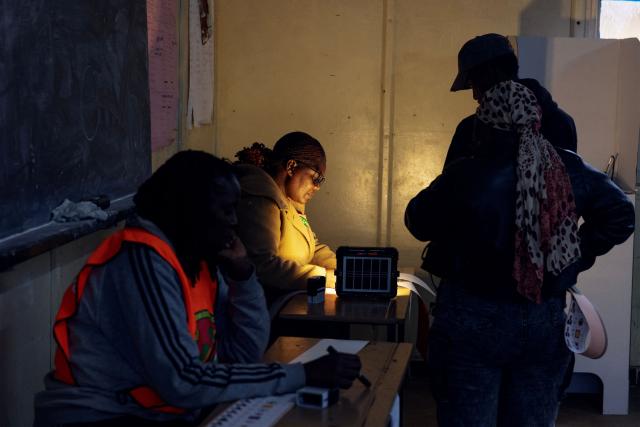 Zambian Electoral Commission officials issue ballots to voters during the Zambian National Elections at Woodlands Primary School polling station, on August 13, 2026. Zambians went to the polls on August 13 with economic hardship testing President Hakainde Hichilema's record as he seeks a second term to govern the copper-rich nation. Polling stations in the southern African nation opened at 6:00 am (0400 GMT) and were due to close 12 hours later, with 8.7 million voters registered to cast their ballots. (Photo by GIANLUIGI GUERCIA / AFP)