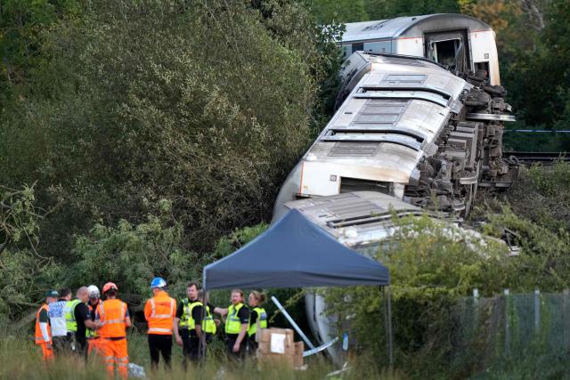 Carriages of a derailed train are pictured on their side, near the town of Lewes, southern England on August 13, 2026. Two people sustained "serious injuries" and nine more were hurt as a busy commuter train from London derailed on August 13, near the southeast English town of Lewes, emergency services said. (Photo by CARLOS JASSO / AFP)