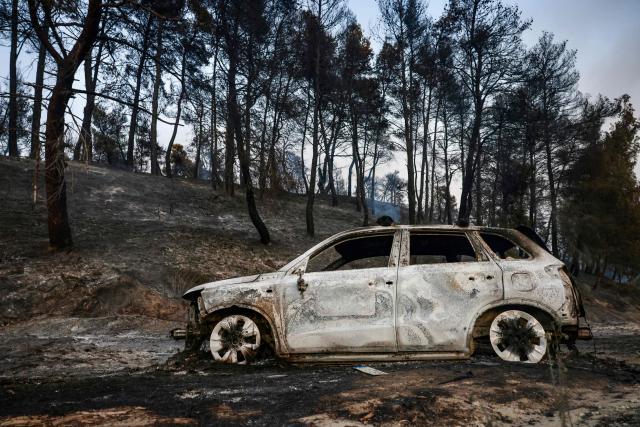 This photograph shows a burnt car after a wildfire near the village of Siviri, northern Greece, on August 13, 2026. A fleet of small boats evacuated hundreds of tourists from beaches in northern Greece as a forest fire bore down on two popular resorts. Water bombing planes and helicopters and almost 150 firefighters battled the flames spreading across the Halkidiki peninsula, south of the city of Thessaloniki, the fire service said. (Photo by Vasilis VERVERIDIS / AFP)
