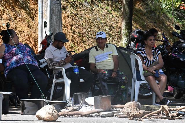 People sit outside their damaged homes at the Altos de Santa Elena neighborhood in Cali, Colombia, on August 13, 2026, three days after a 7.4 earthquake. Rescuers in Colombia were making last-ditch efforts to locate earthquake survivors early on August 13, 2026, as the critical 72-hour window for rescue operations neared its end. (Photo by Joaquin SARMIENTO / AFP)