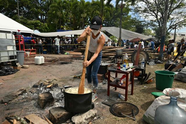 An earthquake victim prepares food in a pot at a shelter three days after a 7.4 earthquake in Pereira, Colombia on August 13, 2026. Rescuers in Colombia were making last-ditch efforts to locate earthquake survivors early on August 13, 2026, as the critical 72-hour window for rescue operations neared its end. (Photo by Luis ACOSTA / AFP)