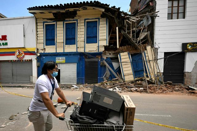 A man pushes a cart past a damaged building after a 7.4 earthquake in Pereira, Colombia on August 13, 2026. Rescuers in Colombia were making last-ditch efforts to locate earthquake survivors early on August 13, 2026, as the critical 72-hour window for rescue operations neared its end. (Photo by Luis ACOSTA / AFP)