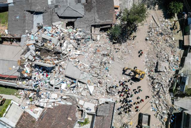 This aerial view shows rescuers searching for survivors amid the rubble of a collapsed building three days after a 7.4 earthquake in Pereira, Colombia on August 13, 2026. Rescuers in Colombia were making last-ditch efforts to locate earthquake survivors early on August 13, 2026, as the critical 72-hour window for rescue operations neared its end. (Photo by Luis ACOSTA / AFP)