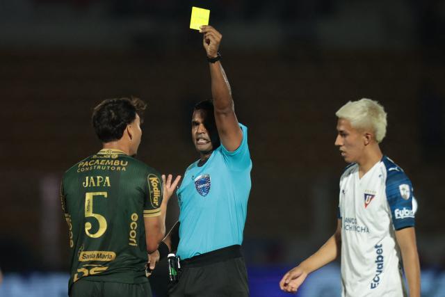 Venezuelan referee Alexis Herrera shows a yellow card to Mirassol's midfielder #05 Japa during the first leg of the Copa Libertadores round of 16 football match between Brazil's Mirassol and Ecuador's Liga de Quito at the Jose Maria de Campos Maia stadium in Mirassol, state of Sao Paulo, Brazil, on August 13, 2026. (Photo by RAPHA MARQUES / AFP)