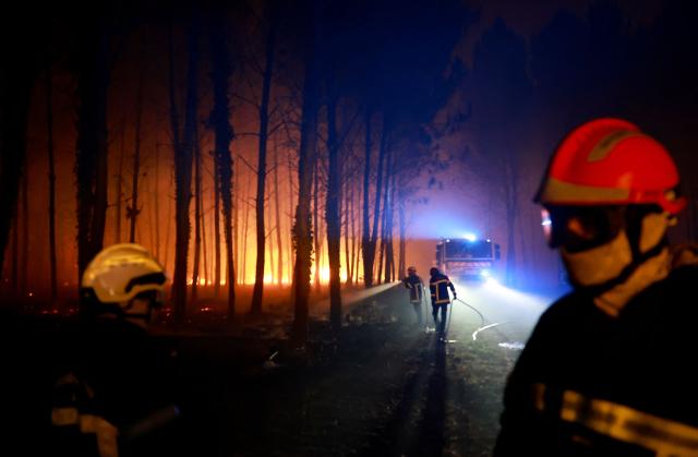 Firefighters battle a wildfire raging through the Landes forest in Luglon, southwestern France, in the early hours of August 14, 2026. The fire that broke out on August 13, 2026 in the Landes forest has now spread across 400 hectares, and 400 people "are being evacuated as a precautionary measure", according to the prefecture of this south-western department. (Photo by ROMAIN PERROCHEAU / AFP)