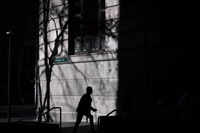 The shadow of a tree is projected onto the wall of a building as a pedestrian walks past on a winter’s day in the central business district (CBD) of Sydney on August 14, 2026. (Photo by DAVID GRAY / AFP)