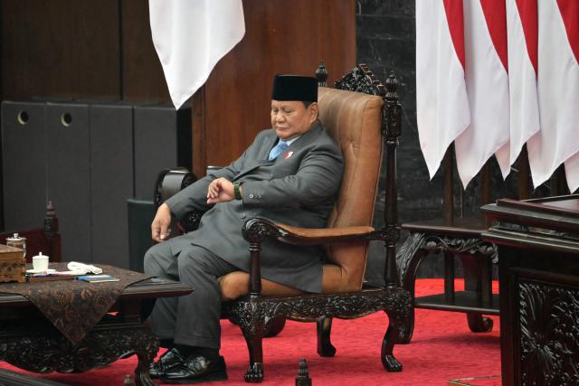 Indonesia's President Prabowo Subianto looks at his watch as he prepares to deliver his annual State of the Nation Address, ahead of the country's Independence Day celebrations, in Jakarta on August 14, 2026. (Photo by BAY ISMOYO / AFP)