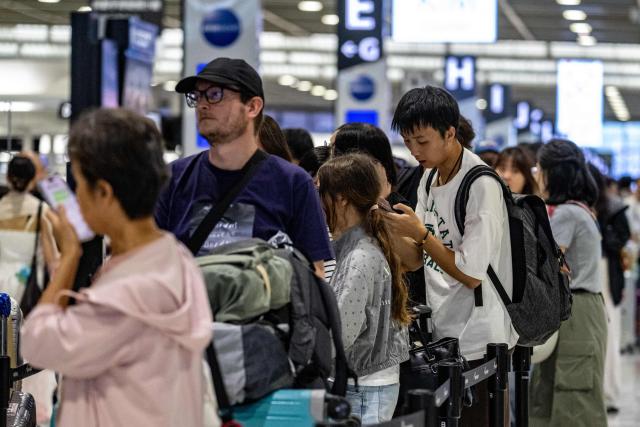 People line up in front of the check-in counter in the departure hall of Narita International Airport in Narita, Chiba prefecture on August 14, 2026. (Photo by Andrew CABALLERO-REYNOLDS / AFP)