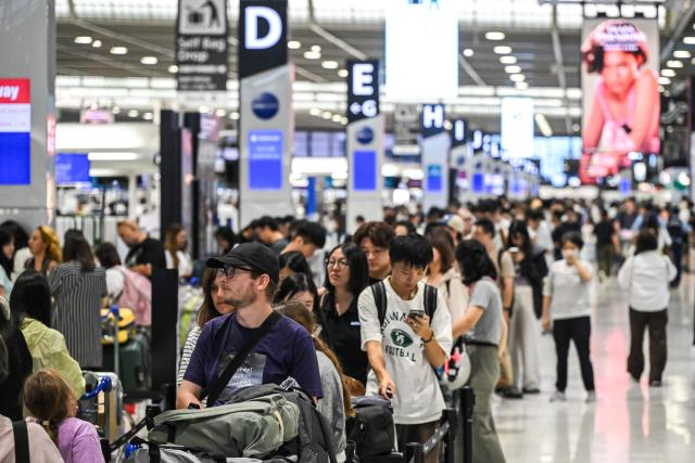 People line up in front of the check-in counter in the departure hall of Narita International Airport in Narita, Chiba prefecture on August 14, 2026. (Photo by Andrew CABALLERO-REYNOLDS / AFP)