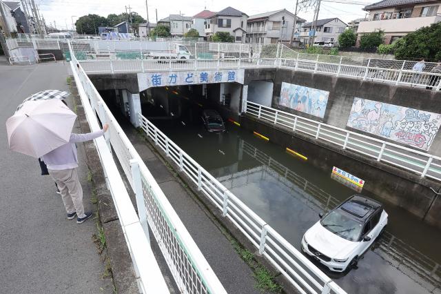 A car is submerged in water in an underpass in Kamagaya city, Chiba Prefecture on August 14, 2026. At least four people died in eastern Japan after "unprecedented" heavy rain that left thousands stranded at Narita airport overnight and snarled up roads and rail services, authorities said. (Photo by JIJI Press / AFP) / Japan OUT