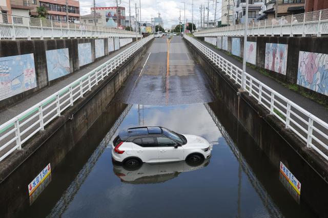 A car is submerged in water in an underpass in Kamagaya city, Chiba Prefecture on August 14, 2026. At least four people died in eastern Japan after "unprecedented" heavy rain that left thousands stranded at Narita airport overnight and snarled up roads and rail services, authorities said. (Photo by JIJI Press / AFP) / Japan OUT