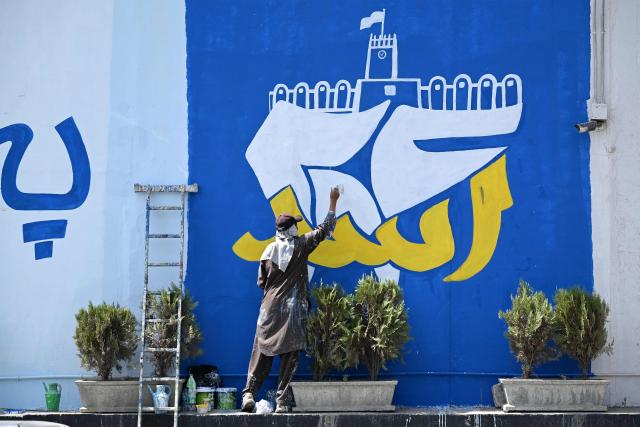 An Afghan man paints a mural commemorating the fifth anniversary marking the Taliban's return to power, along a street in Kabul on August 13, 2026. (Photo by Wakil KOHSAR / AFP)