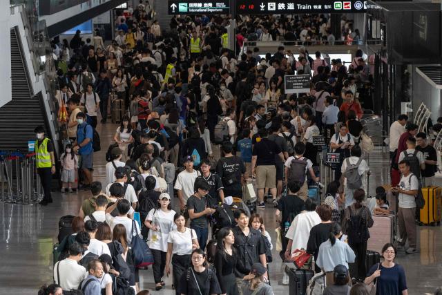 Passengers line up to enter the train station at the Narita International Airport in Narita, Chiba prefecture on August 14, 2026, after many of the train lines to the airport were closed. At least four people died in eastern Japan after "unprecedented" heavy rain that left thousands stranded at Narita airport overnight and snarled up roads and rail services, authorities said. (Photo by ANDREW CABALLERO-REYNOLDS / AFP)