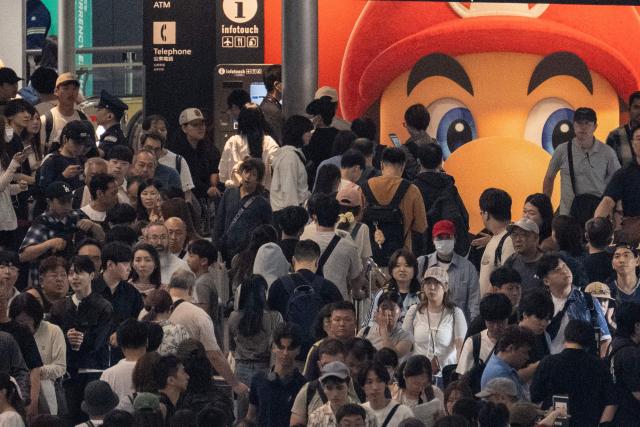 Passengers line up to enter the train station at the Narita International Airport in Narita, Chiba prefecture on August 14, 2026, after many of the train lines to the airport were closed. At least four people died in eastern Japan after "unprecedented" heavy rain that left thousands stranded at Narita airport overnight and snarled up roads and rail services, authorities said. (Photo by ANDREW CABALLERO-REYNOLDS / AFP)
