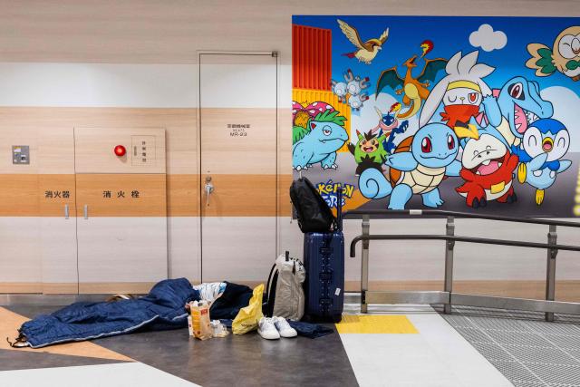 TOPSHOT - A passenger sleeps at the Narita International Airport in Narita, Chiba prefecture on August 14, 2026. At least four people died in eastern Japan after "unprecedented" heavy rain that left thousands stranded at Narita airport overnight and snarled up roads and rail services, authorities said. (Photo by ANDREW CABALLERO-REYNOLDS / AFP)