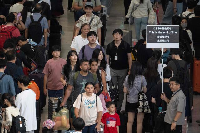 Passengers line up to enter the train station at the Narita International Airport in Narita, Chiba prefecture on August 14, 2026, after many of the train lines to the airport were closed. At least four people died in eastern Japan after "unprecedented" heavy rain that left thousands stranded at Narita airport overnight and snarled up roads and rail services, authorities said. (Photo by ANDREW CABALLERO-REYNOLDS / AFP)