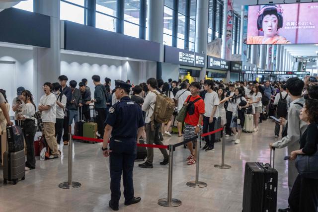 Passengers line up to enter the train station at the Narita International Airport in Narita, Chiba prefecture on August 14, 2026, after many of the train lines to the airport were closed. At least four people died in eastern Japan after "unprecedented" heavy rain that left thousands stranded at Narita airport overnight and snarled up roads and rail services, authorities said. (Photo by ANDREW CABALLERO-REYNOLDS / AFP)