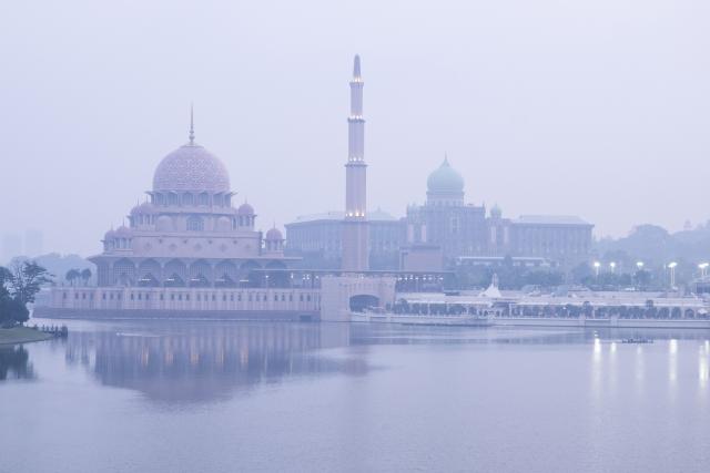 This photo shows the Putra Mosque (L) and Malaysia’s Prime Minister’s Office covered in haze in Putrajaya on August 14, 2026, as authorities in Malaysia warned of high levels of air pollution from regional wildfires. (Photo by Mohd RASFAN / AFP)