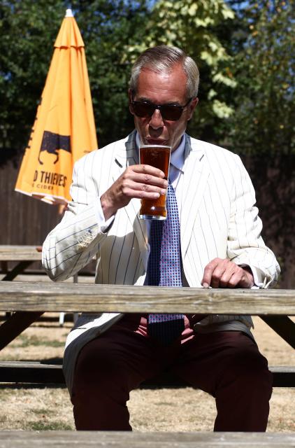 (FILES) Reform UK leader Nigel Farage sits and poses with a pint in the garden of The Ship pub after casting his vote in the Clacton by-election earlier in the morning, in the village of Kirby-le-Soken, Essex on August 13, 2026. British hard-right leader Nigel Farage has won a snap UK election he triggered in Clacton on August 14, comfortably beating satirical opponent Count Binface as was expected, according to results. (Photo by Henry NICHOLLS / AFP)