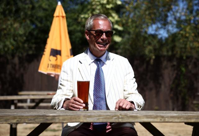 (FILES) Reform UK leader Nigel Farage sits and poses with a pint in the garden of The Ship pub after casting his vote in the Clacton by-election earlier in the morning, in the village of Kirby-le-Soken, Essex on August 13, 2026. British hard-right leader Nigel Farage has won a snap UK election he triggered in Clacton on August 14, comfortably beating satirical opponent Count Binface as was expected, according to results. (Photo by Henry NICHOLLS / AFP)