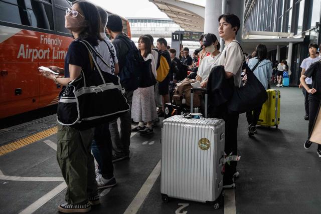 Passengers wait to board a bus at the Narita International Airport in Narita, Chiba prefecture on August 14, 2026, after many of the train lines to the airport were closed. At least four people died in eastern Japan after "unprecedented" heavy rain that left thousands stranded at Narita airport overnight and snarled up roads and rail services, authorities said. (Photo by ANDREW CABALLERO-REYNOLDS / AFP)