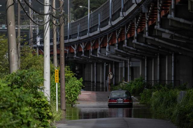 An abandoned car is seen partially submerged on a flooded road in Sakura, Chiba prefecture on August 14, 2026. At least four people died in eastern Japan after "unprecedented" heavy rain that left thousands stranded at Narita airport overnight and snarled up roads and rail services, authorities said. (Photo by ANDREW CABALLERO-REYNOLDS / AFP)