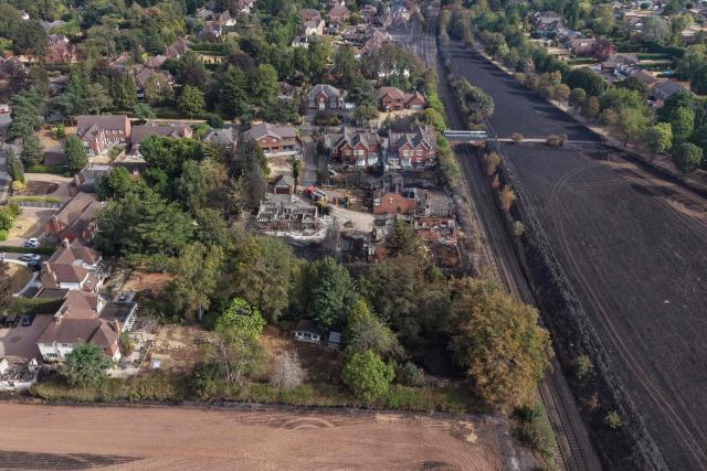 An aerial view shows a group of fire-damaged house, beside a burnt field, south of Stourbridge town centre in central England on August 14, 2026. Firefighters continued Friday to extinguish wildfires that began on August 13, tearing through several homes, with residents evacuated and "extensive" damage reported. (Photo by Darren Staples / AFP)