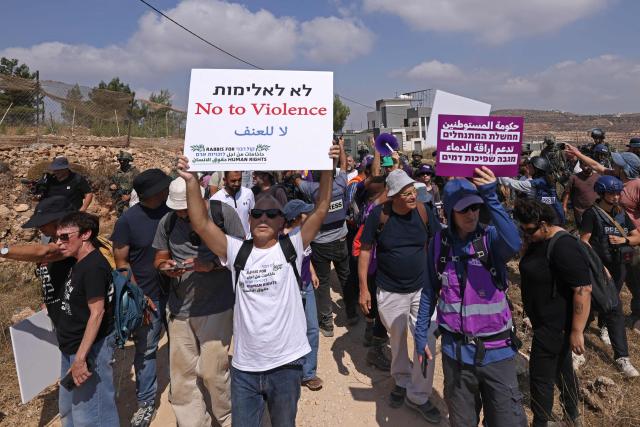 Israeli leftist activists and solidarity volunteers gather in front of a besieged Palestinian house by Israeli settlers in the village of Qusra, south of Nablus, in the occupied West Bank, on August 14, 2026. Israeli forces on August 13 moved against rogue settlers laying siege to Palestinians amid unusually strong US criticism, even as Israel inaugurated an emblematic settlement elsewhere in the West Bank. Settlers at Qusra near Nablus since August 9 have blockaded Palestinian homes, including one owned by a US citizen, with residents saying they have been cut off from food and other supplies. (Photo by JAAFAR ASHTIYEH / AFP)