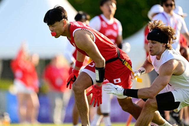 Japan's Tsubasa Brennan (L) and Canada's Emile Chenevert fight for the ball during the men's match between Japan and Canada at the "IFAF World Flag" World Championship in flag football in Duesseldorf, western Germany, on August 14, 2026. (Photo by Ina FASSBENDER / AFP)