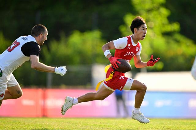 Japan's Kodai Okumura (R) runs with the ball during the men's match between Japan and Canada at the "IFAF World Flag" World Championship in flag football in Duesseldorf, western Germany, on August 14, 2026. (Photo by Ina FASSBENDER / AFP)