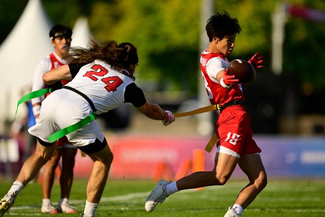 Canada's Marc-Antoine Dequoy (L) and Japan's Kodai Okumura (R) fight for the ball during the men's match between Japan and Canada at the "IFAF World Flag" World Championship in flag football in Duesseldorf, western Germany, on August 14, 2026. (Photo by Ina FASSBENDER / AFP)